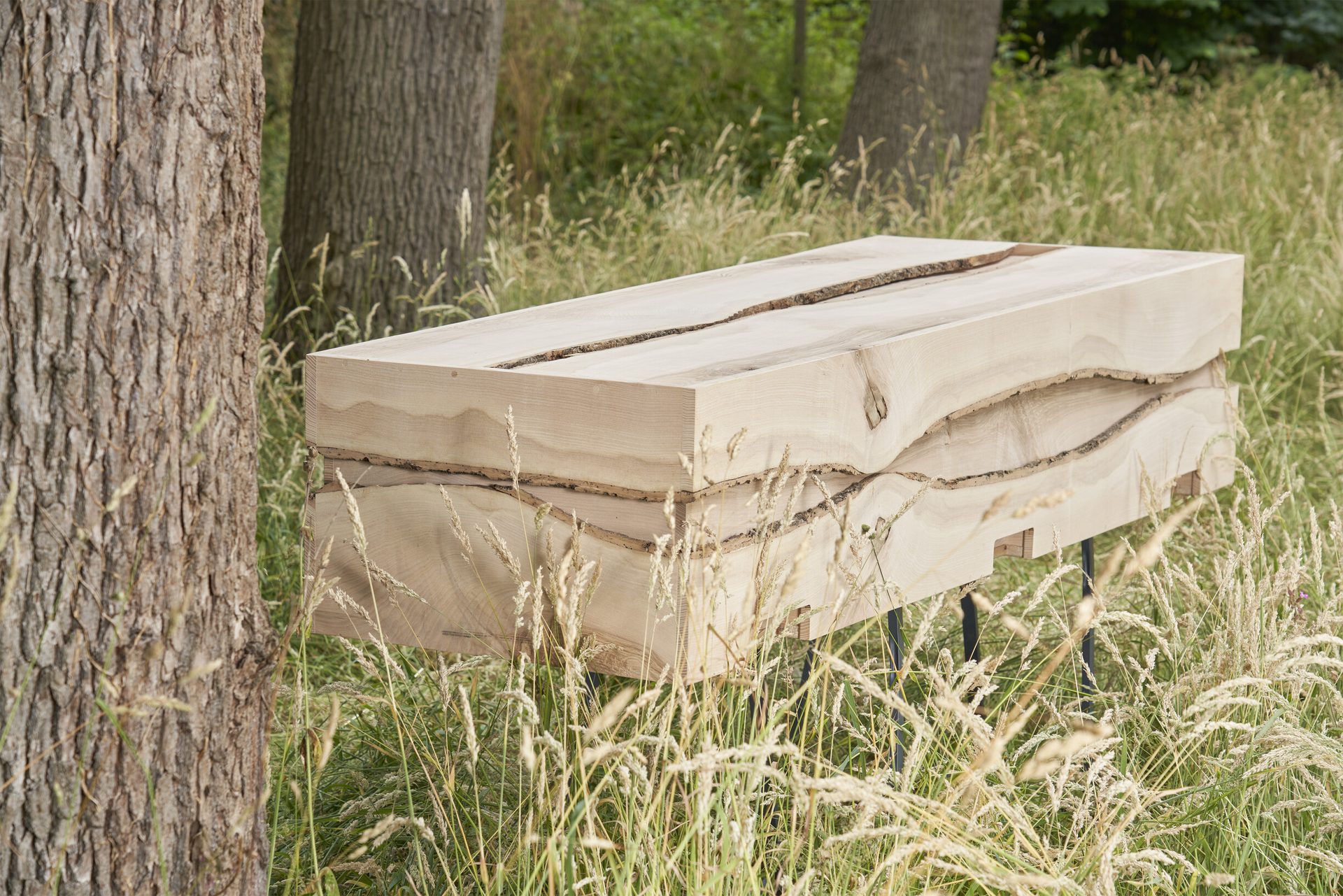 Een houten kist in hoog gras op een natuurbegraafplaats