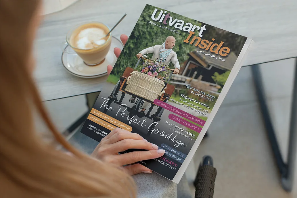 Iemand leest Uitvaart-Inside bij een kop koffie