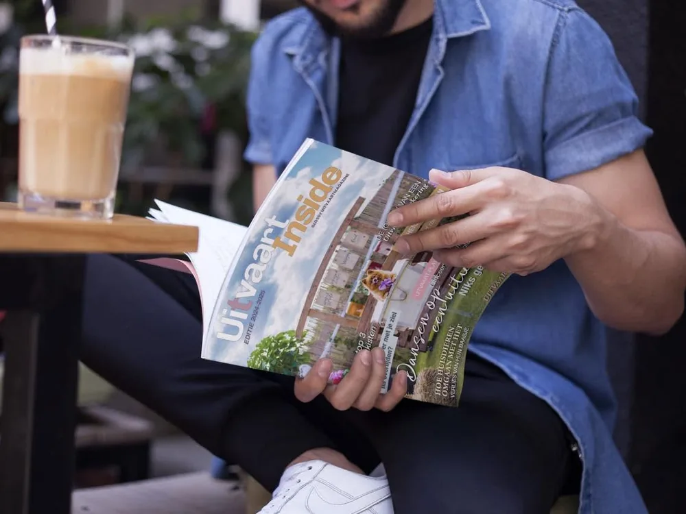Een man leest Uitvaart-Inside op een terras