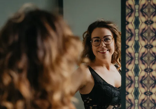 Vrouw met bril kijkt naar haar spiegelbeeld in een spiegel.